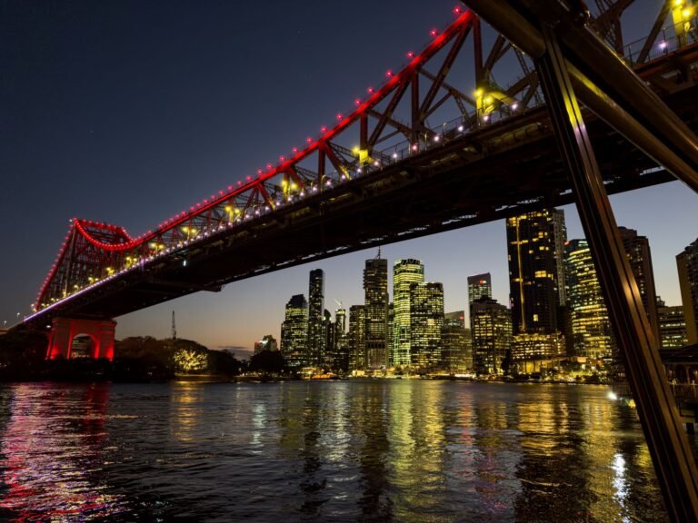 Large bridge at night overlooking large city, bright lights