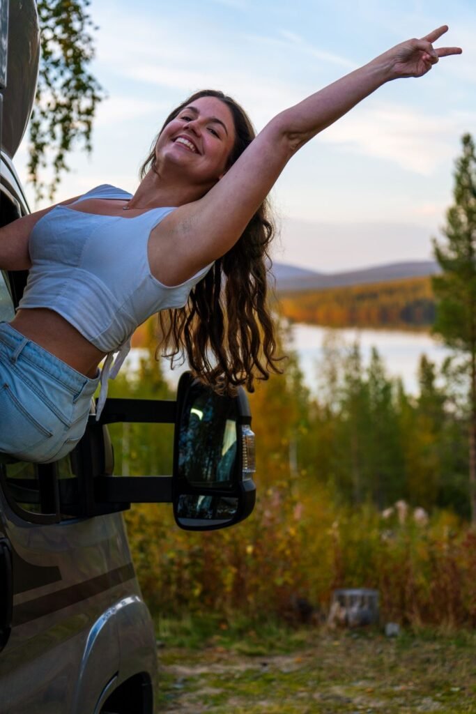 Girl in van hanging out window with a peace sign, big smile