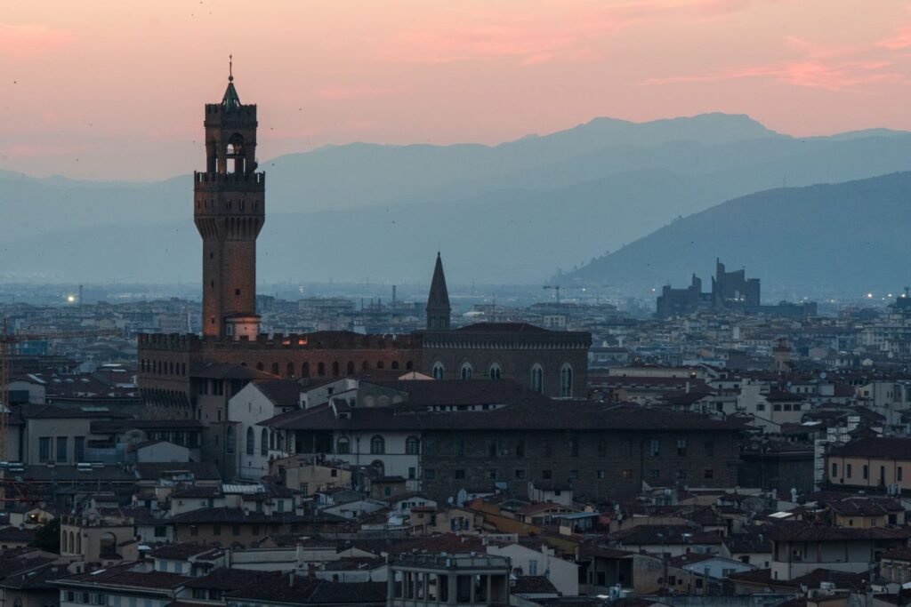 large castle tower at sunset, mountains in the background, cities to visit in italy