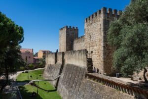 Large castle from side on, moat that is full of green grass