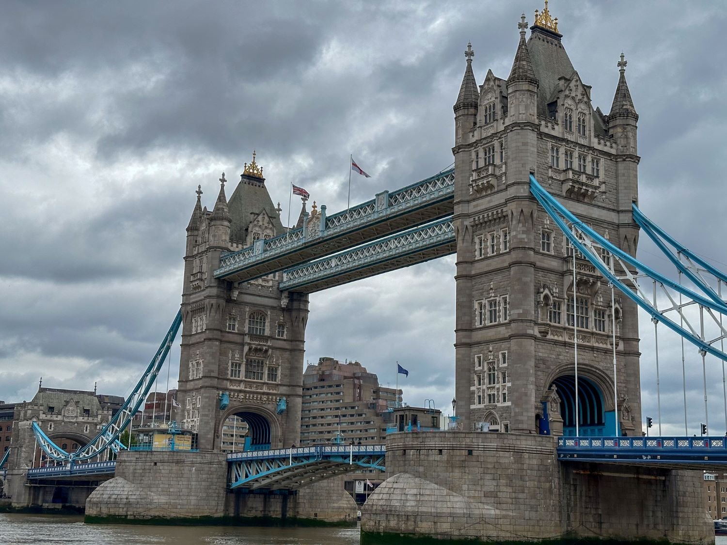 Large bridge with blue steel beams and 2 castle like towers, overcast day.