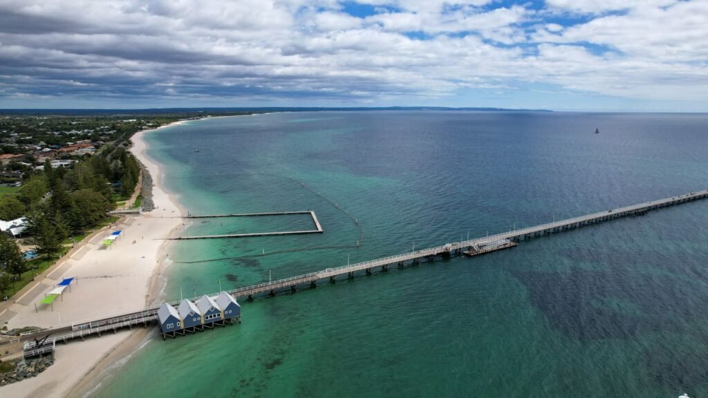 Very long jetty, blue ocean, white sand, semi overcast day