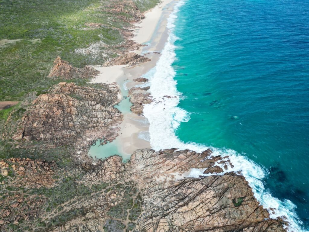 Drone photo of beach, bright blue water, white sand