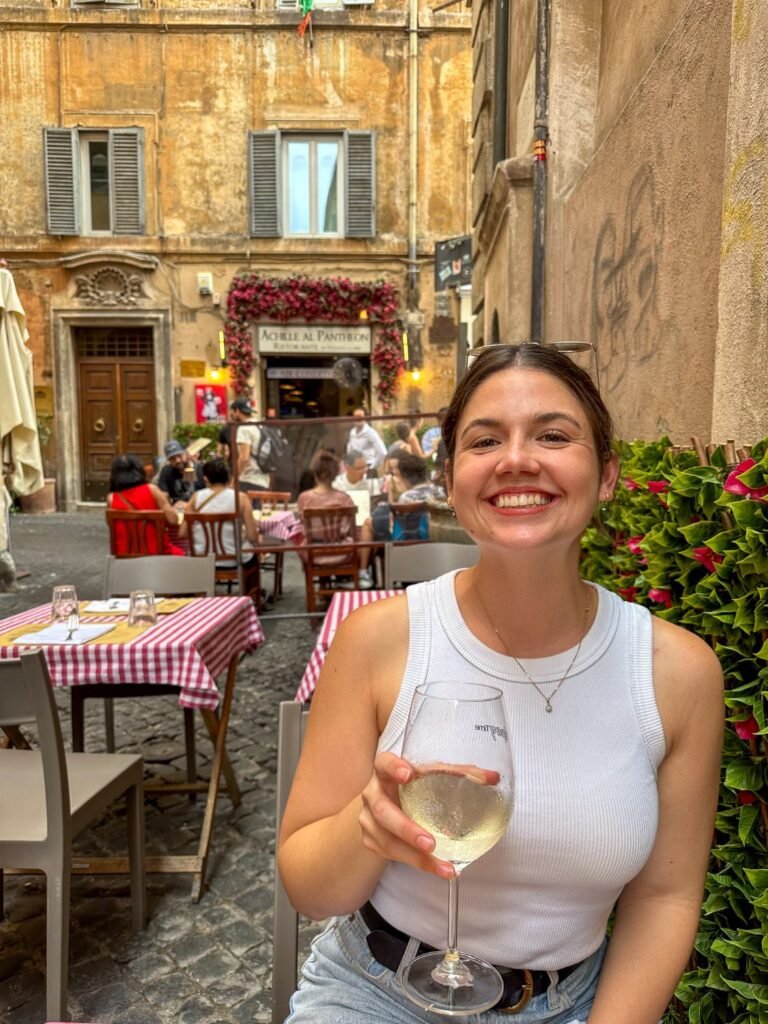 Girl smiling, holding a glass of white wine at outdoor restaurant