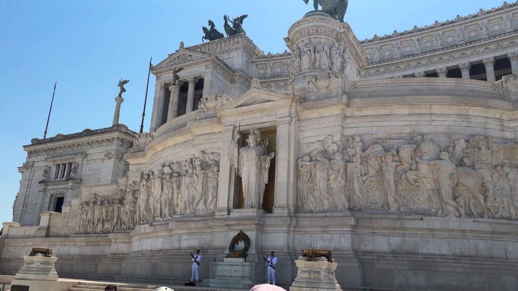 Large, intricate monument. 2 well-dressed soldiers with rifles guarding eternal flame.