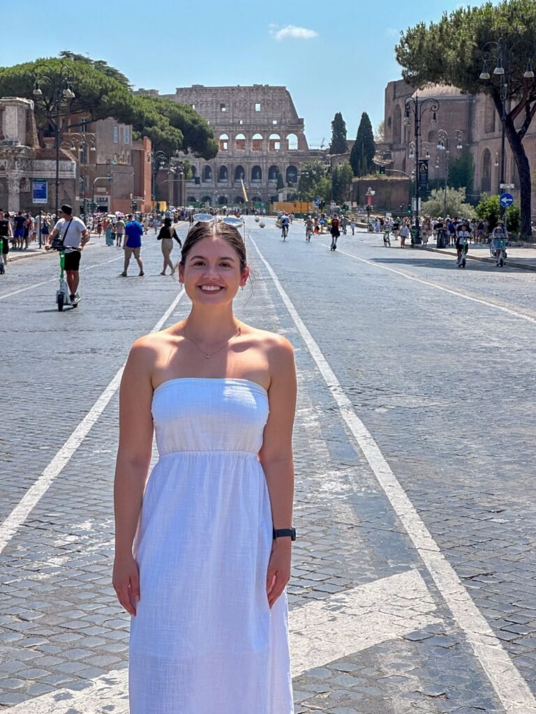 Girl posing in front of Colosseum, standing on Via dei Fori Imperiali