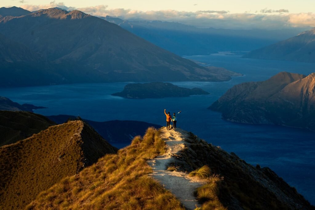 2 people standing on peak of large mountain range